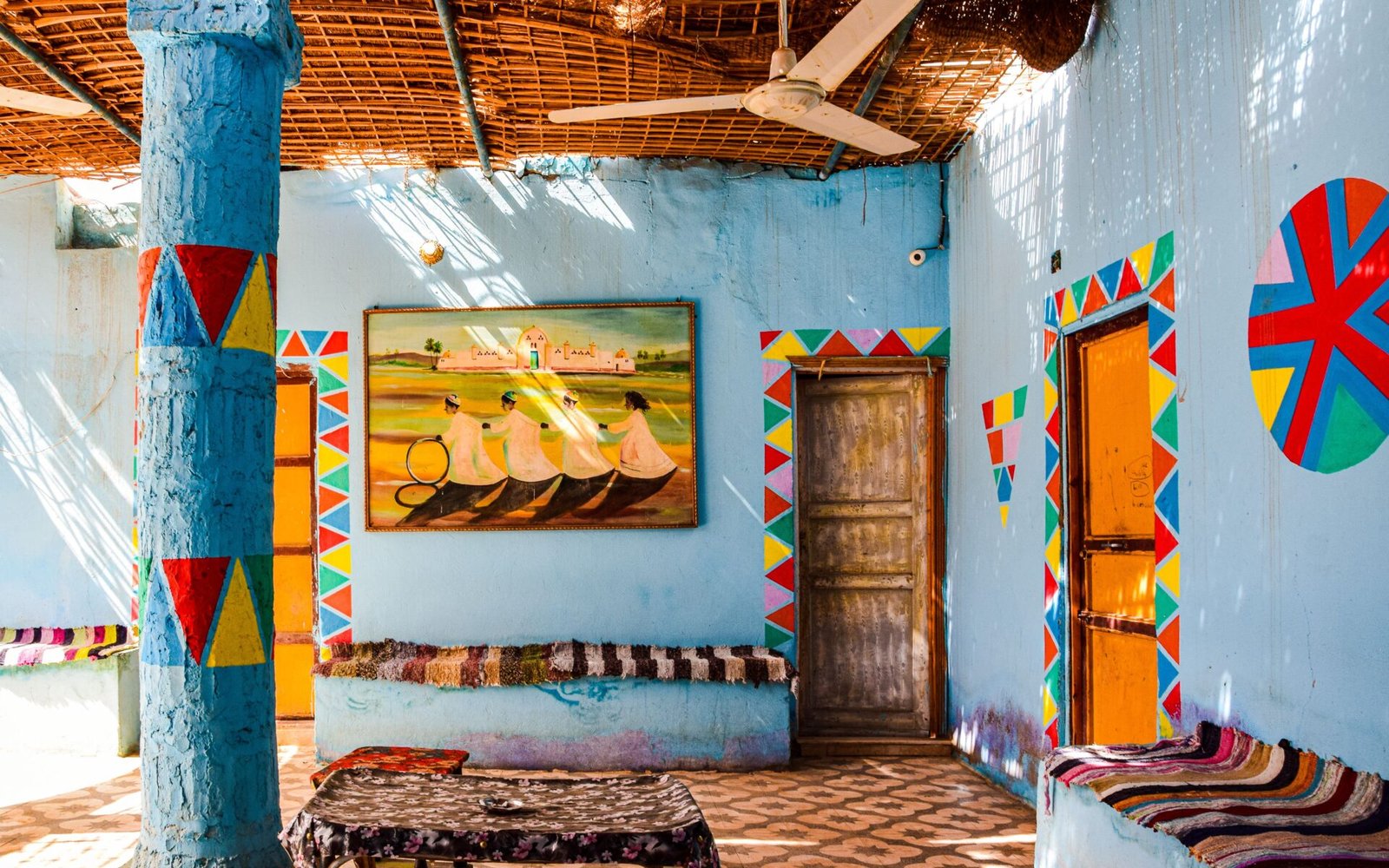 Colorful Nubian style interior with ornate patterns and sunlight streaming through woven roof.
