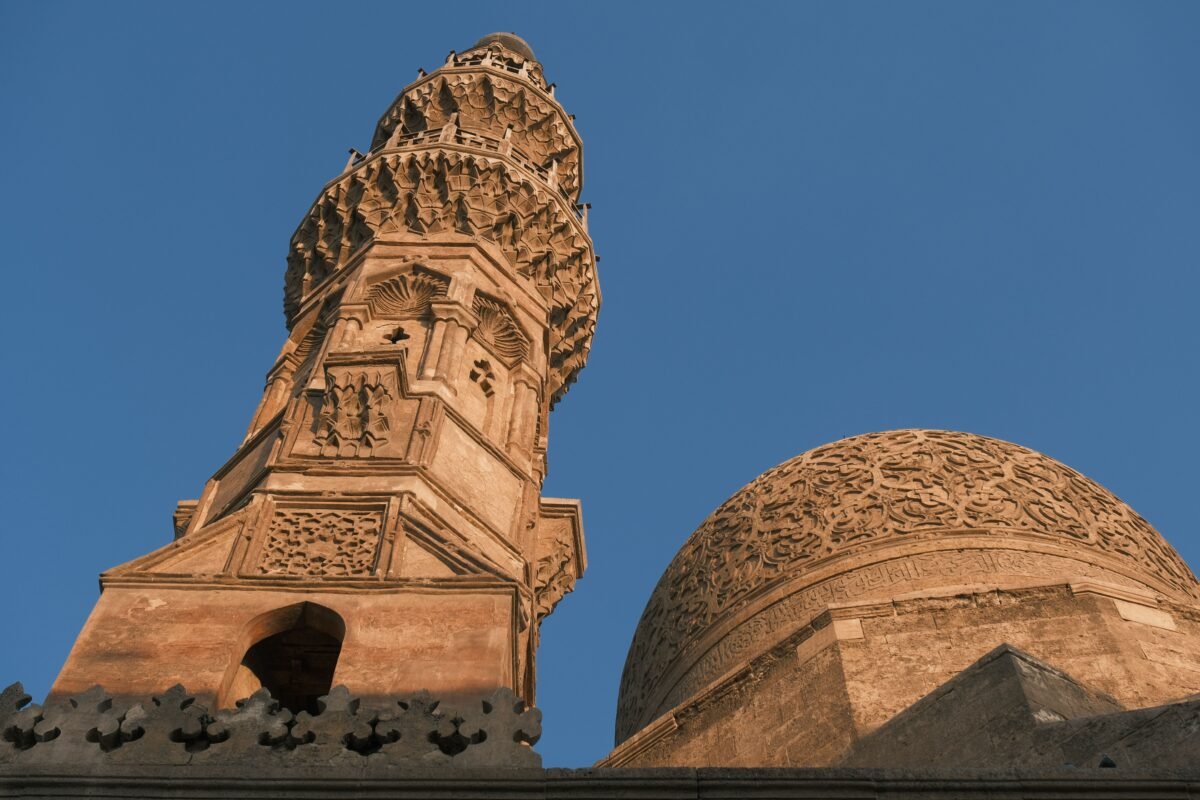 The intricate detail of a mosque's minaret and dome beautifully captured against a clear blue sky.